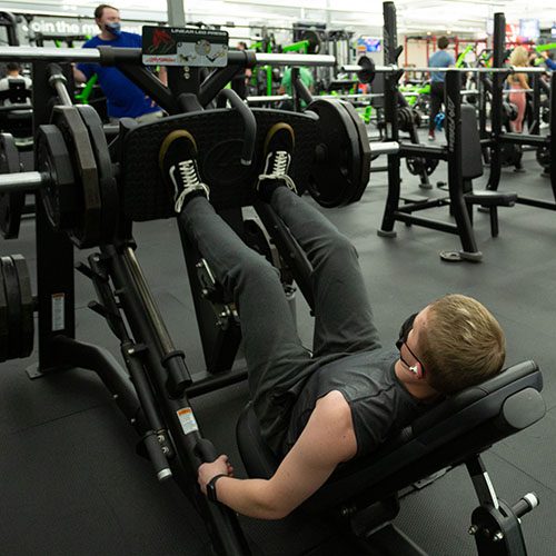 man using leg workout machine in muv fitness center