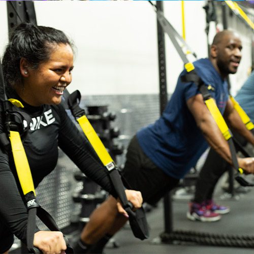 adults using strength building machine in gym near me