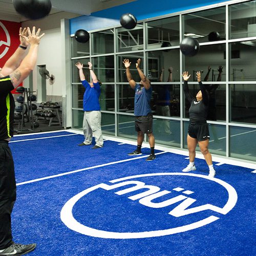 group tossing weighted balls into the air in gym near me