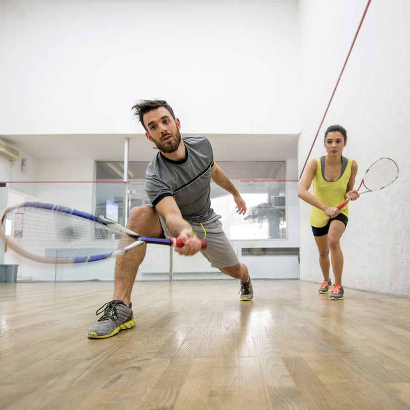 man and woman playing racquetball inside a gym