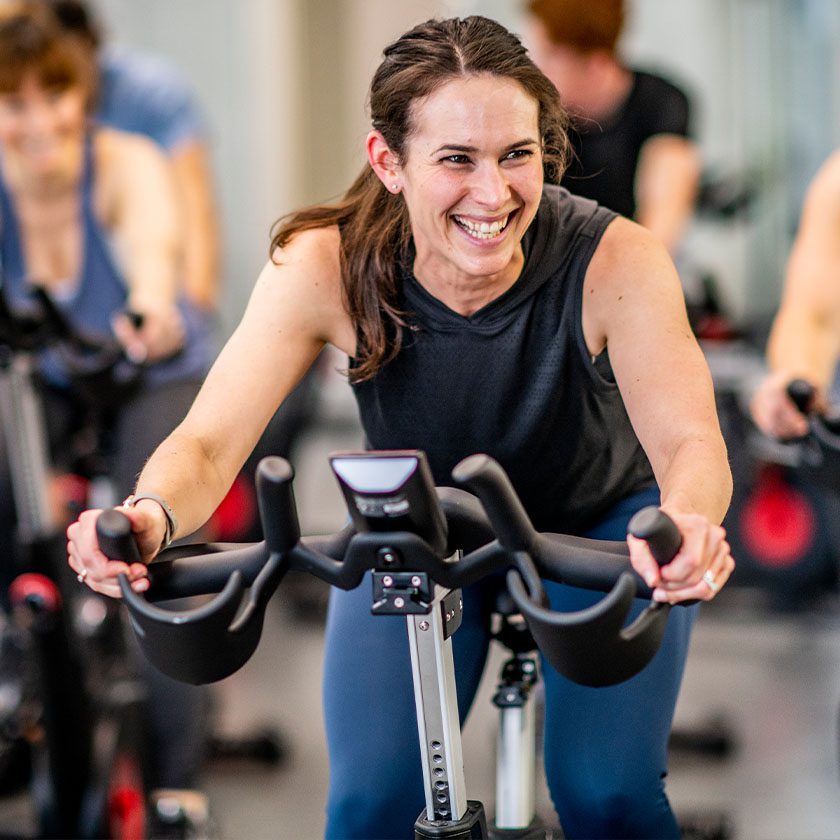 person smiling in a spin class in gym near me