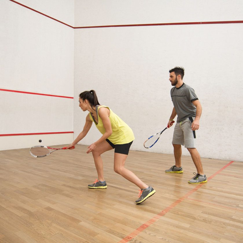 man and woman playing racquetball inside a health club