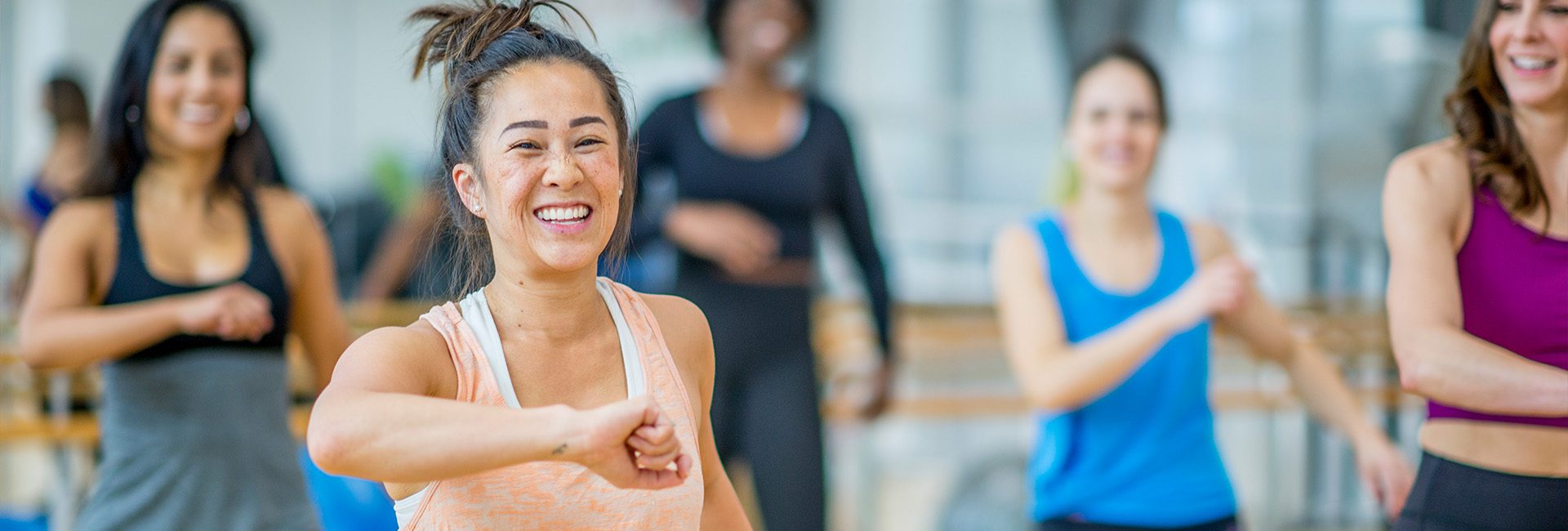 gym member smiling in a group fitness zumba class