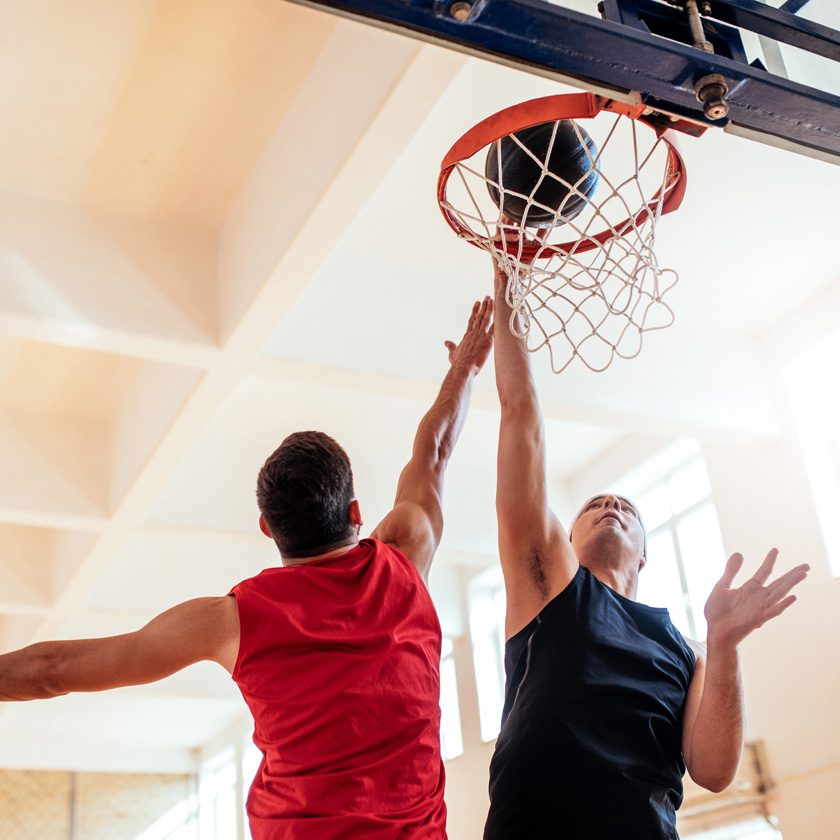 indoor basketball court with a man performing a lay up and being blocked by another man at a health club in killian