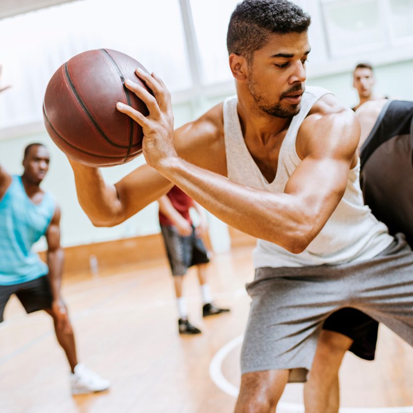 indoor basketball court where a man is being defend by another man while setting up a pass at a fitness center in north spokane