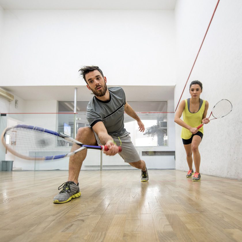 a couple playing racquetball at a health club indoor court in north spokane