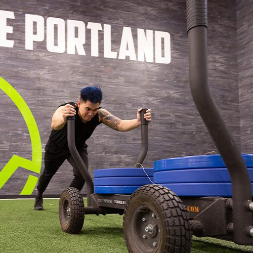 man working out on functional turf floor pushing weights