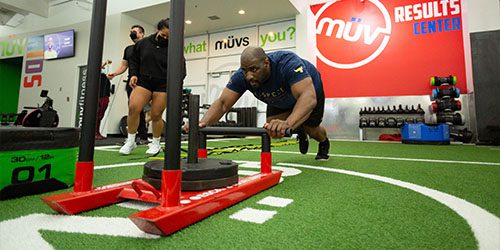 man pushing weights on turf floor