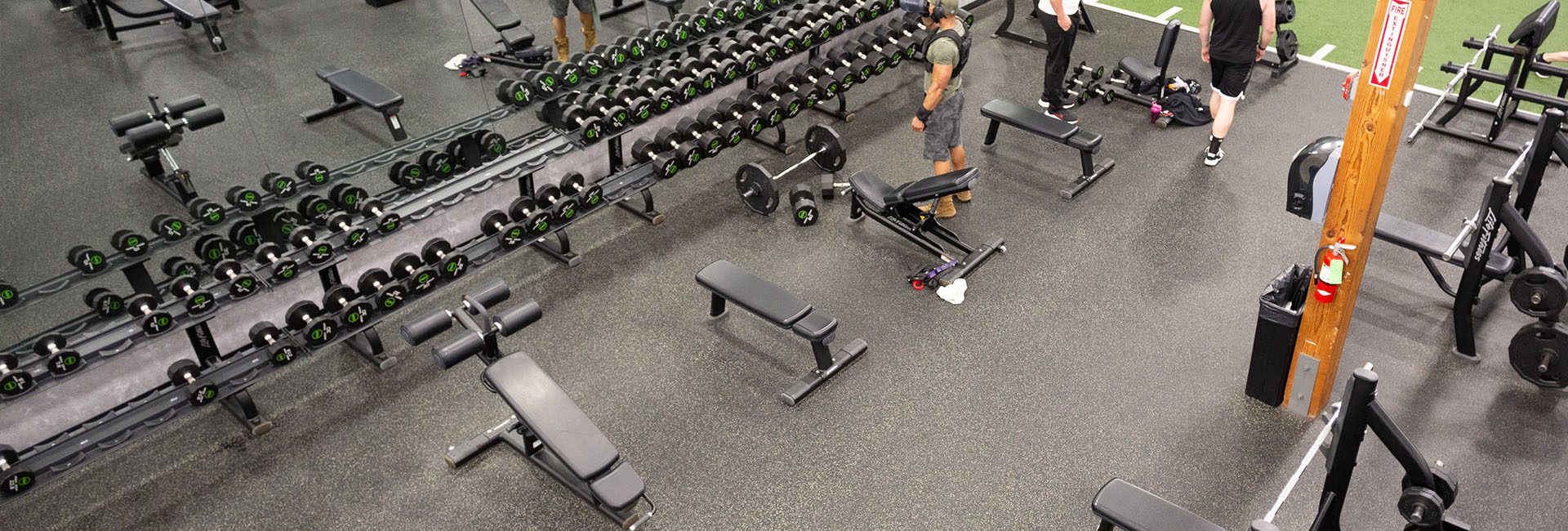people working out in the strength training area of a modern gym