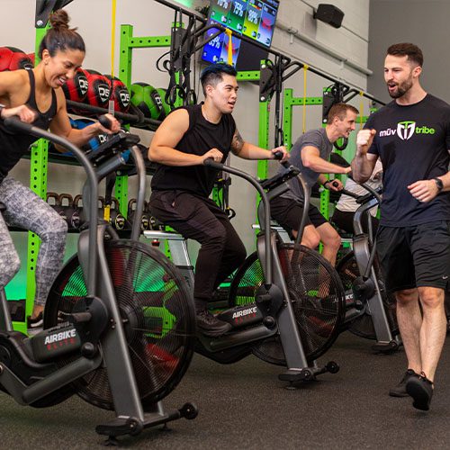 certified trainer training a group of people on exercise bikes