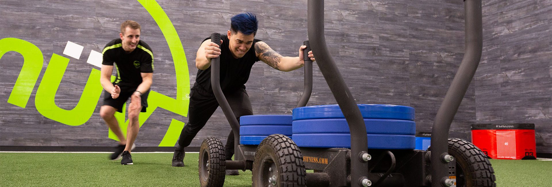 a man is pushing equipment with a personal trainer