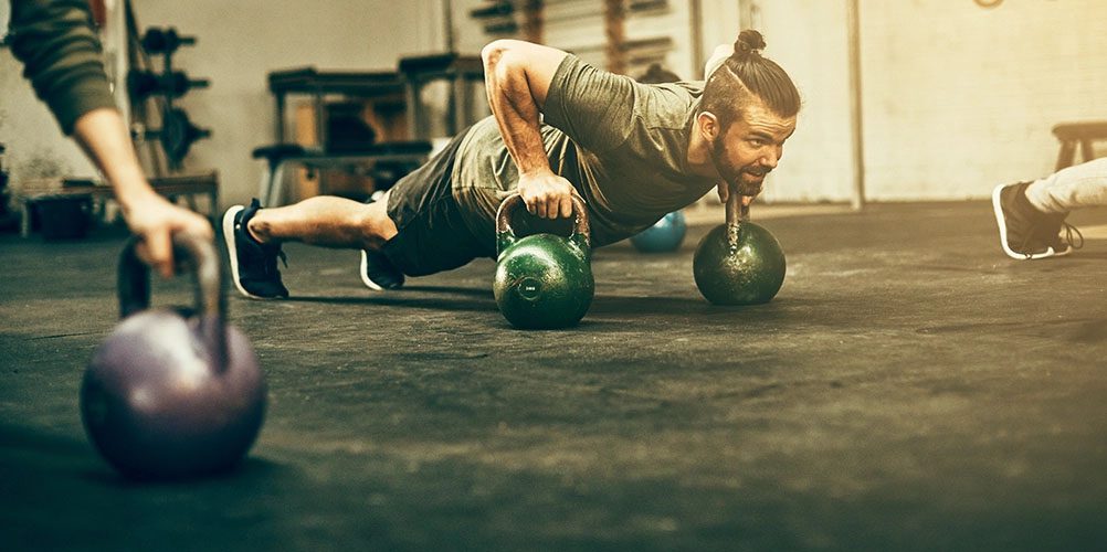 man doing push up with kettle-ball