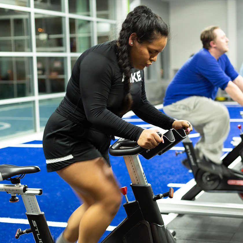 woman on an exercise bike for gym training in a modern gym near me